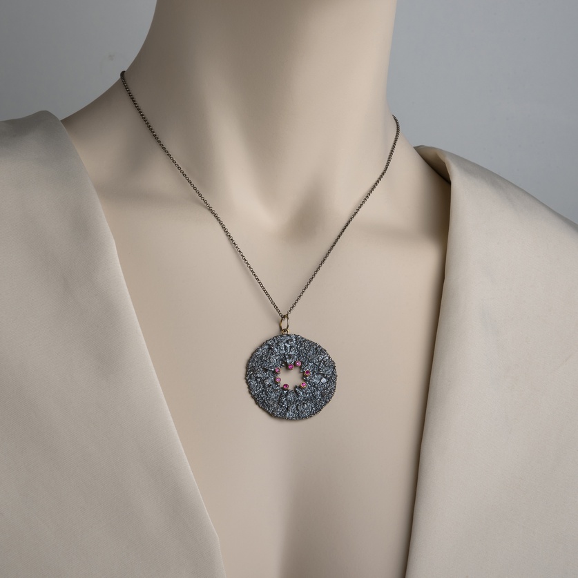 Round pendant with rough surface in silver, gold inlay and rubies